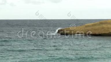 海浪拍打着大海中的一个岩石小岛。 地中海上的风暴。 大海是绿松石。